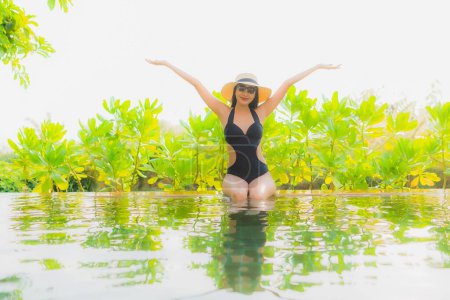 Téléchargez les photos : Portrait belle jeune femme asiatique se détendre dans la piscine à l'hôtel station pour les vacances de loisirs voyage - en image libre de droit