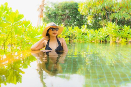 Téléchargez les photos : Portrait belle jeune femme asiatique se détendre dans la piscine à l'hôtel station pour les vacances de loisirs voyage - en image libre de droit