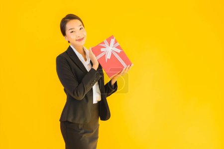 Foto de Retrato hermosa joven asiática mujer show rojo regalo caja con feliz sonrisa en amarillo aislado fondo - Imagen libre de derechos
