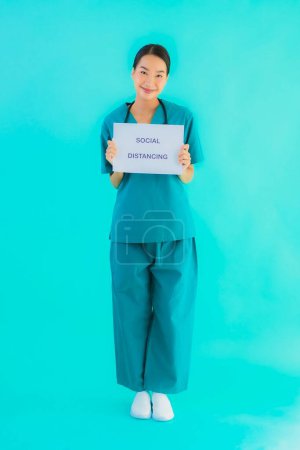 Photo for Portrait beautiful young asian doctor woman show sign with Social distancing on blue isolated background - Royalty Free Image