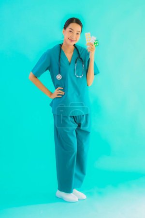 Foto de Retrato hermosa joven asiática médico mujer con píldora o droga y medicina en azul aislado fondo - Imagen libre de derechos