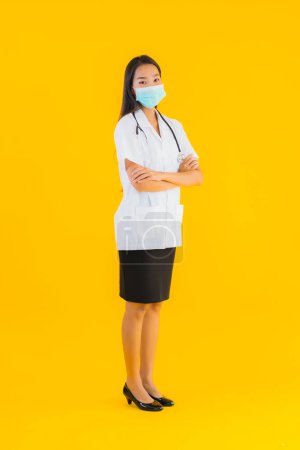 Photo for Portrait beautiful young asian doctor woman with mask for protect covid19 or coronavirus on yellow isolated background - Royalty Free Image