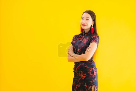 Foto de Retrato hermosa mujer asiática joven usar vestido chino con acción para el concepto de año nuevo chino sobre fondo aislado amarillo - Imagen libre de derechos