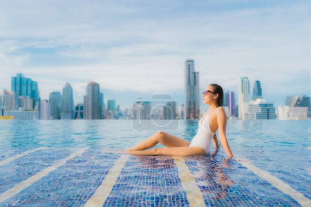 Photo for Portrait beautiful young asian woman relax happy smile leisure around outdoor swimming pool with cityscape - Royalty Free Image