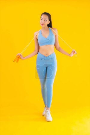 Photo for Portrait beautiful young asian woman wear sportwear with rope ready for exercise on yellow isolated background - Royalty Free Image