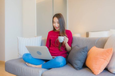 Photo for Portrait beautiful young asian woman use laptop computer on sofa in living area at bedroom interior - Royalty Free Image