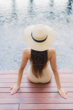 Téléchargez les photos : Portrait belle jeune femme asiatique se détendre sourire autour de la piscine extérieure dans la station hôtelière en voyage de vacances - en image libre de droit
