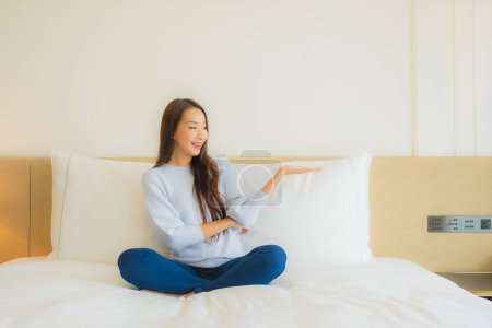Téléchargez les photos : Portrait belle jeune asiatique femme relax sourire loisirs sur lit dans chambre intérieur - en image libre de droit