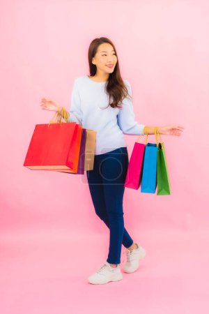 Téléchargez les photos : Portrait belle jeune femme asiatique avec sac à provisions coloré sur fond isolé de couleur rose - en image libre de droit