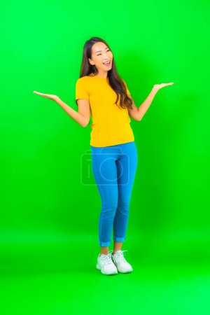 Téléchargez les photos : Portrait belle jeune femme asiatique sourire avec action sur fond vert isolé - en image libre de droit