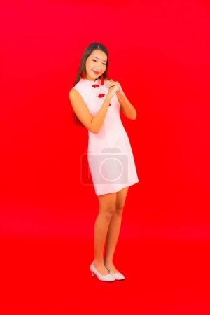 Téléchargez les photos : Portrait belle jeune femme asiatique porter des vêtements du Nouvel An chinois sur fond rouge - en image libre de droit