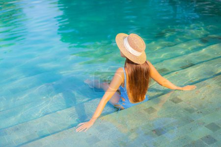 Téléchargez les photos : Portrait belle jeune femme asiatique relax sourire profiter des loisirs autour de la piscine presque mer plage océan vue pour les vacances de loisirs - en image libre de droit