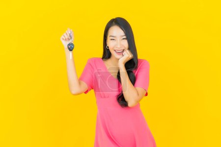 Foto de Retrato hermosa joven mujer asiática sonrisa con llave del coche sobre fondo de color amarillo - Imagen libre de derechos