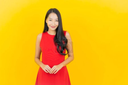 Foto de Retrato hermosa joven mujer asiática llevar vestido rojo sonrisa con acción sobre fondo de color amarillo - Imagen libre de derechos