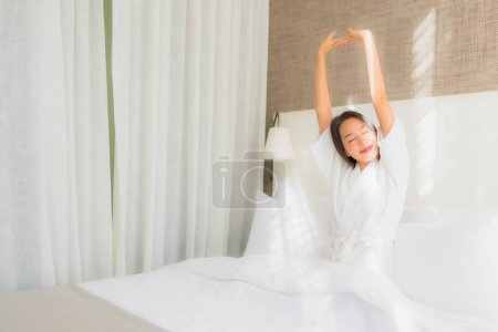 Foto de Retrato hermosa joven asiática mujer relajarse sonrisa en la cama en el interior del dormitorio - Imagen libre de derechos