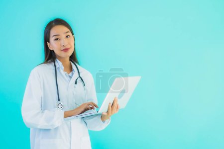 Photo for Portrait beautiful young asian doctor woman with laptop for use in clinic or hospital on blue isolated background - Royalty Free Image