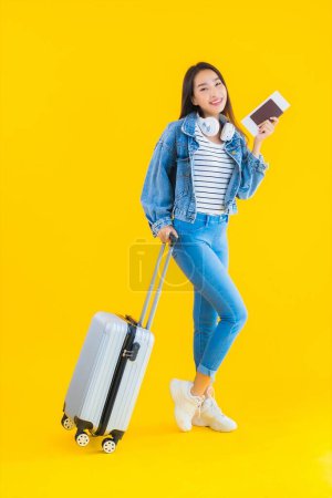 Foto de Retrato hermosa joven mujer asiática de viaje y ocio con bolsa de equipaje y pasaporte, tarjeta de embarque sobre fondo aislado amarillo - Imagen libre de derechos