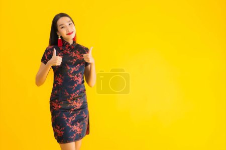 Téléchargez les photos : Portrait belle jeune femme asiatique porter robe chinoise avec action pour le nouveau concept de l'année chinoise sur fond jaune isolé - en image libre de droit