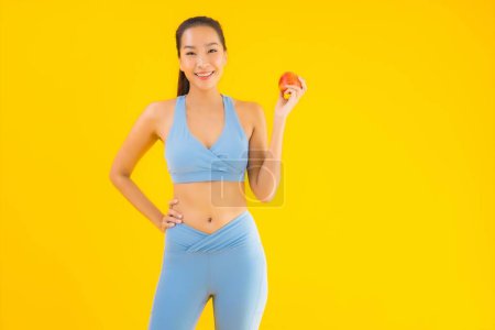 Foto de Retrato hermosa joven mujer asiática usar ropa deportiva listo para el ejercicio con fruta de manzana aislado fondo - Imagen libre de derechos