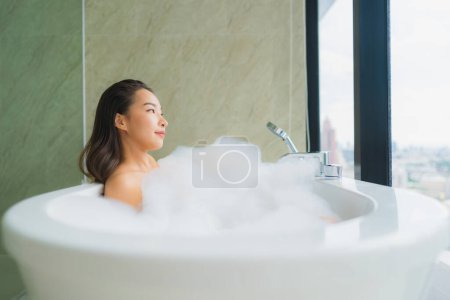 Foto de Retrato hermosa joven mujer asiática relajarse y ocio en la decoración de la bañera en el interior del baño - Imagen libre de derechos