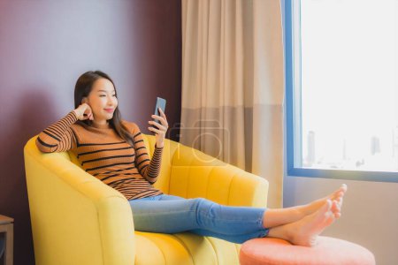Photo for Portrait beautiful young asian woman relax smile in action on sofa in living room interior - Royalty Free Image