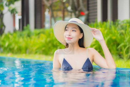 Foto de Retrato hermosa joven mujer asiática relajarse disfrutar de sonrisa alrededor de la piscina al aire libre en el complejo hotelero en vacaciones de ocio - Imagen libre de derechos