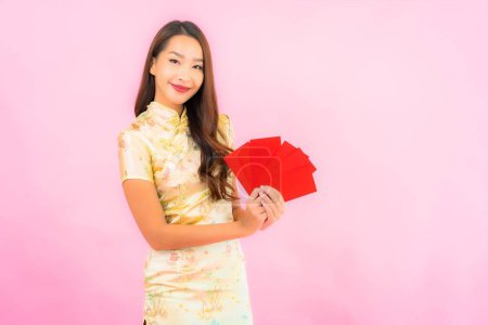 Téléchargez les photos : Portrait belle jeune femme asiatique avec des enveloppes rouges en chinois concept de nouvelle année sur fond rose - en image libre de droit