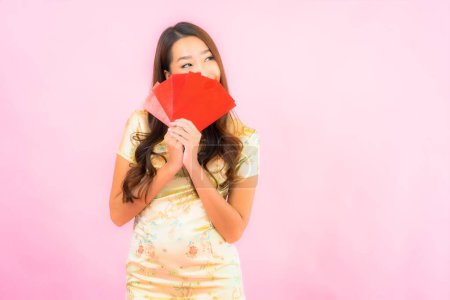 Téléchargez les photos : Portrait belle jeune femme asiatique avec des enveloppes rouges en chinois concept de nouvelle année sur fond rose - en image libre de droit