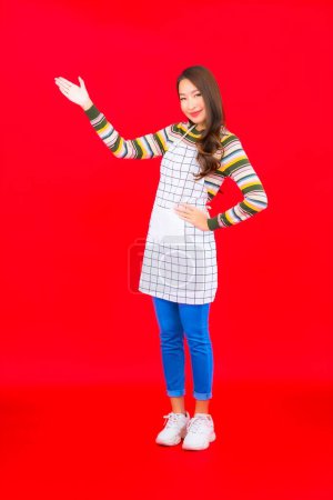 Foto de Retrato hermosa joven mujer asiática usar delantal sobre fondo rojo - Imagen libre de derechos