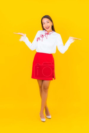 Téléchargez les photos : Portrait belle jeune femme asiatique sourire en action sur fond jaune - en image libre de droit