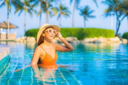Téléchargez les photos : Portrait belle jeune femme asiatique relax sourire loisirs autour de la piscine extérieure avec vue sur la mer océan - en image libre de droit