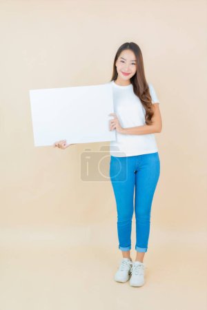 Foto de Retrato hermosa joven asiática mujer mostrar vacío blanco cartel tarjeta papel en crema fondo - Imagen libre de derechos