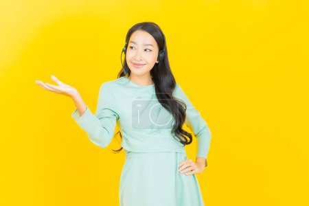 Foto de Retrato hermosa mujer asiática joven con centro de atención al cliente centro de atención al cliente en fondo de color amarillo - Imagen libre de derechos