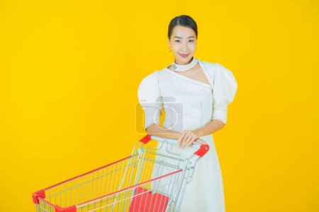 Foto de Retrato hermosa joven asiática mujer sonrisa con cesta de supermercado en color de fondo - Imagen libre de derechos