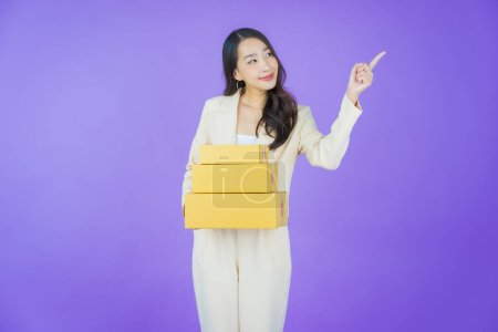 Téléchargez les photos : Portrait belle jeune femme asiatique avec boîte prête pour l'expédition sur fond de couleur - en image libre de droit