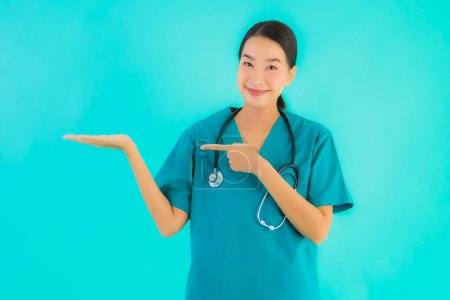 Téléchargez les photos : Portrait belle jeune asiatique médecin femme heureux sourire pour le travail à l'hôpital et clinique sur fond bleu isolé - en image libre de droit