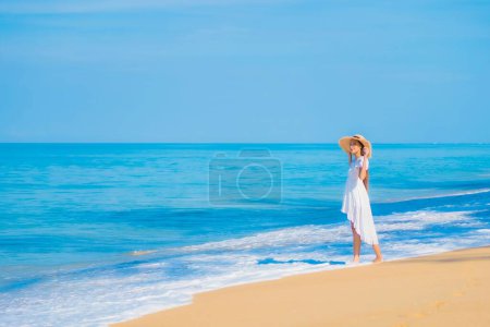 Téléchargez les photos : Portrait belle jeune femme asiatique se détendre sourire loisirs autour de la mer plage océan avec nuage blanc sur ciel bleu en vacances Voyage - en image libre de droit