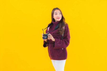 Photo for Portrait beautiful young asian woman with backpack and camera for travel in vacation on yellow isolated background - Royalty Free Image