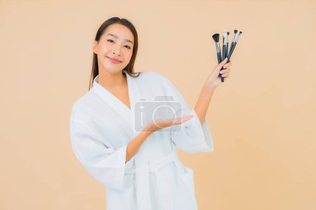 Foto de Retrato hermosa joven asiática mujer con maquillaje cepillo en color aislado fondo - Imagen libre de derechos