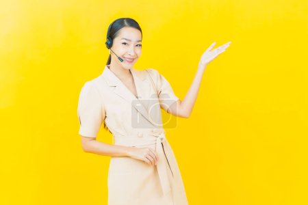 Photo for Portrait beautiful young asian woman with call center customer care service center on yellow color background - Royalty Free Image