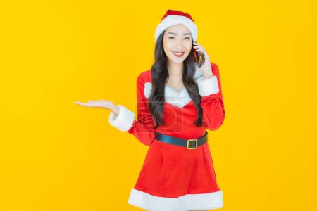 Téléchargez les photos : Portrait belle jeune femme asiatique porter costume de Noël avec téléphone mobile sur fond de couleur - en image libre de droit