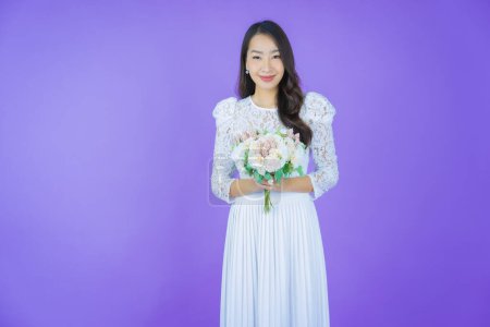 Téléchargez les photos : Portrait belle jeune femme asiatique sourire avec fleur sur fond de couleur - en image libre de droit