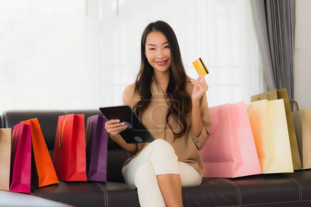 Photo for Portrait beautiful young asian woman online shopping with credit card and smartphone around shopping bag in living room - Royalty Free Image