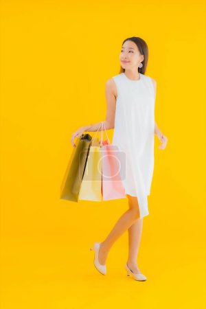 Photo for Portrait beautiful young asian woman with shopping bag from retails department store on yellow isolated background - Royalty Free Image