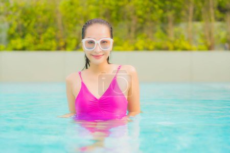 Téléchargez les photos : Portrait belle jeune femme asiatique relax sourire autour de la piscine extérieure dans la station hôtelière pour des vacances de voyage - en image libre de droit