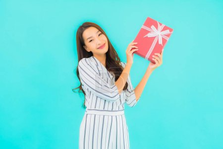 Téléchargez les photos : Portrait belle jeune femme asiatique avec boîte cadeau rouge sur fond bleu isolé - en image libre de droit