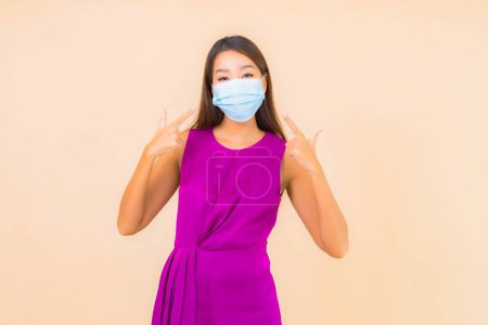 Foto de Retrato hermosa mujer asiática joven usar máscara para proteger de covid19 o corona virus sobre fondo de color - Imagen libre de derechos