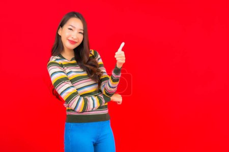 Téléchargez les photos : Portrait belle jeune femme asiatique sourire avec action sur fond rouge isolé - en image libre de droit