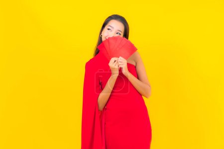 Téléchargez les photos : Portrait belle jeune femme asiatique avec lettre enveloppe rouge sur fond jaune - en image libre de droit