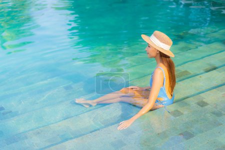 Photo for Portrait beautiful young asian woman relax smile enjoy leisure around swimming pool nearly sea beach ocean view for leisure vacation - Royalty Free Image